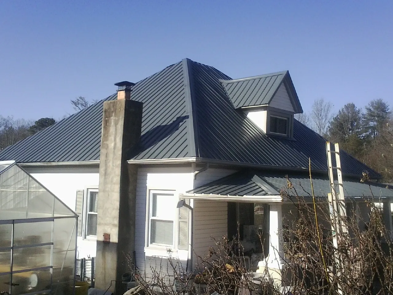 Dark blue standing seam metal roof on a white farmhouse with dormer — Slate & Tile Roof Repair by Roofing Brothers in Berea