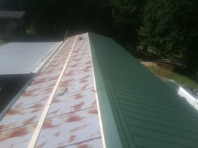 Old rusted panels beside newly installed green metal roofing — Wind Damage Roof Repair by Roofing Brothers in Berea