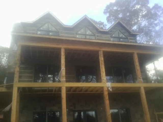 Dormers and porch framing on a large log home under construction — Roof Coating work by our crew in Berea