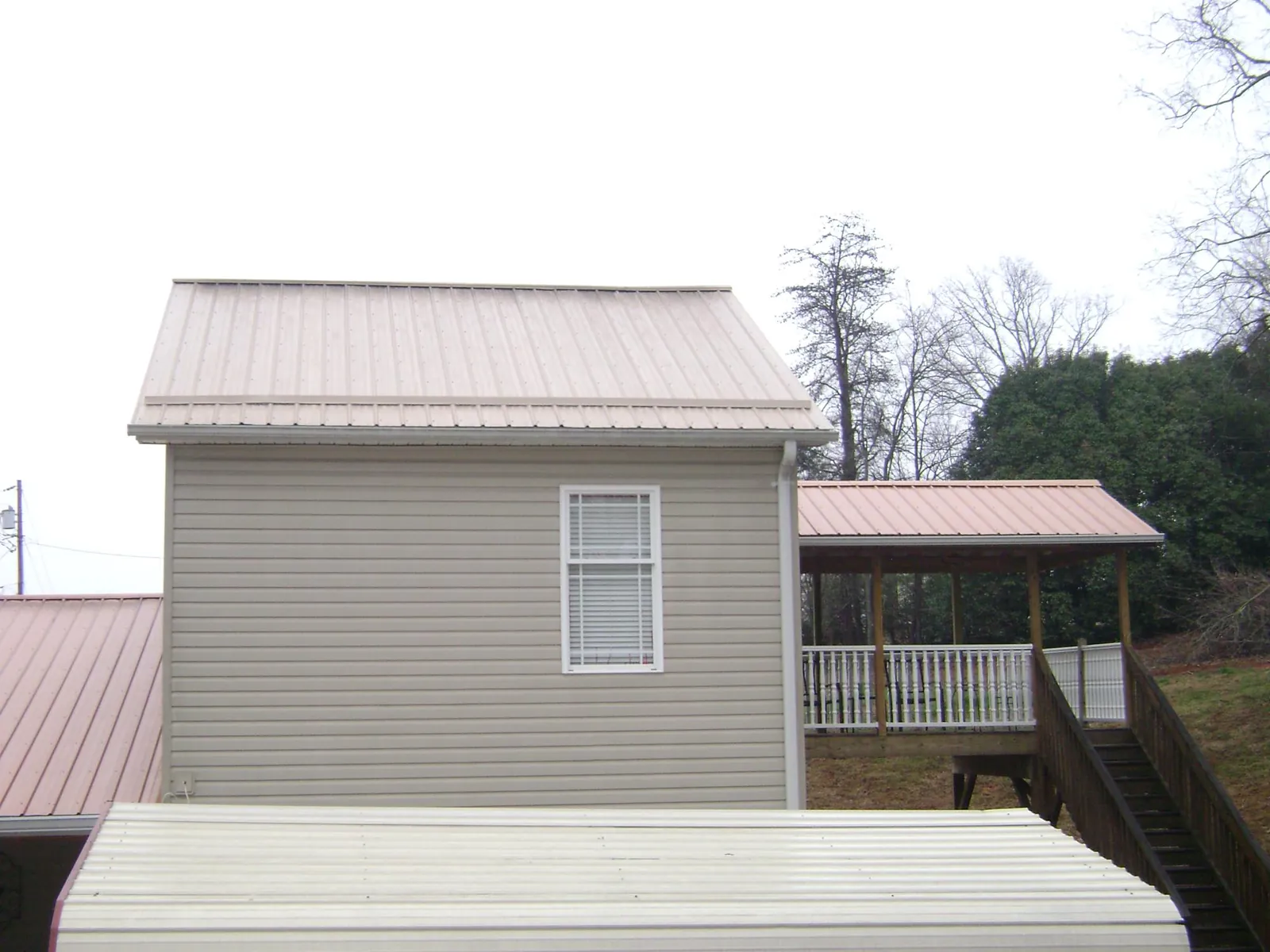 Tan metal roofs on a two story addition and attached porch, from a Roof Replacement job in Berea